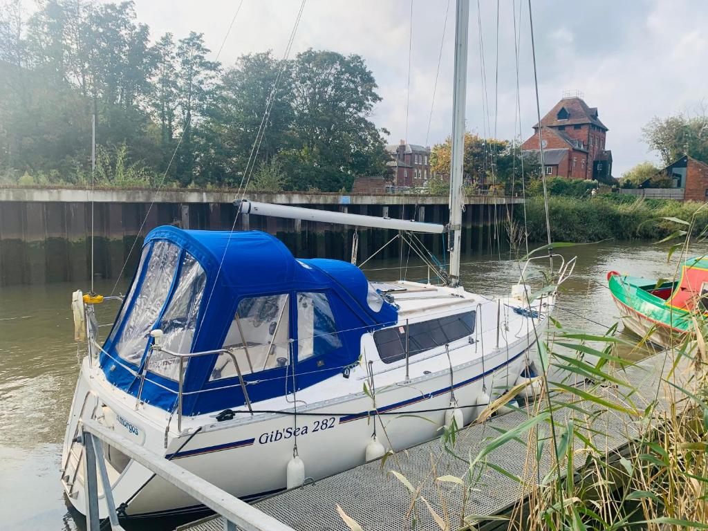 a boat is docked at a dock in the water at Cosy Sailing Boat Glamping Accommodation on the River in Sandwich in Sandwich