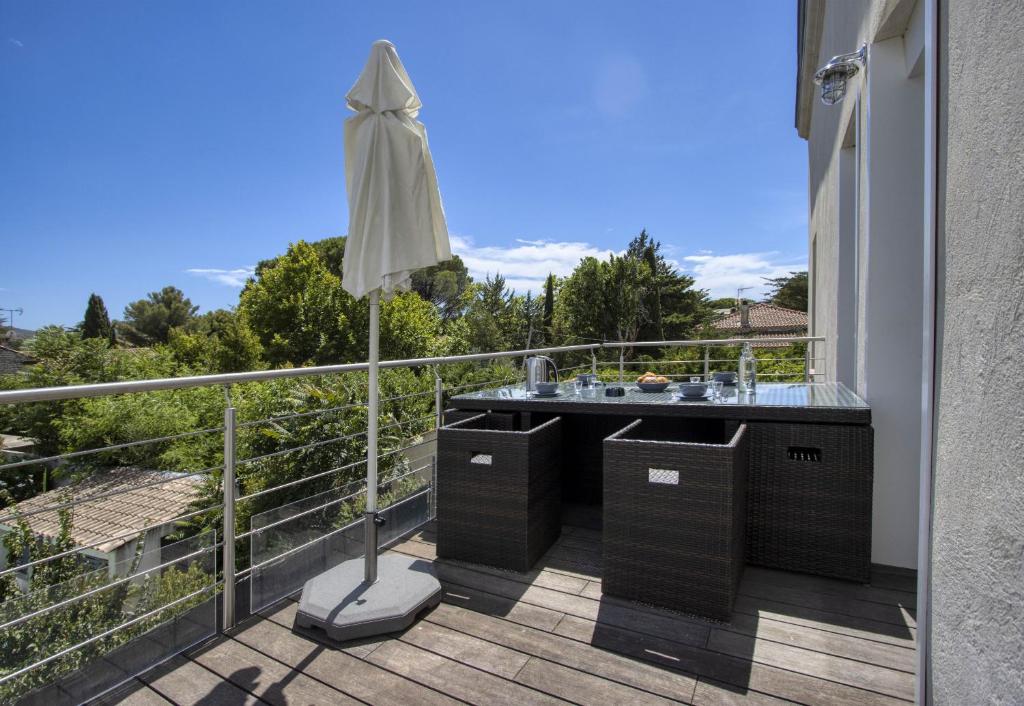 - un balcon avec un lavabo et un parasol dans l'établissement Galant Appartement en bord de mer avec terrasse, à Saint-Cyr-sur-Mer