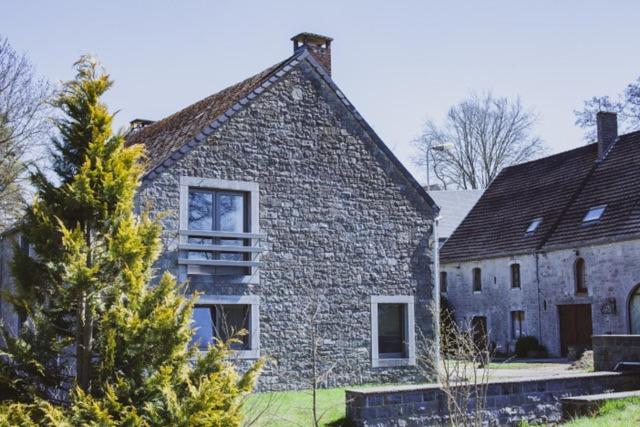 een stenen huis met een boom ervoor bij La petite maison du moulin de Scoville. in Hamois