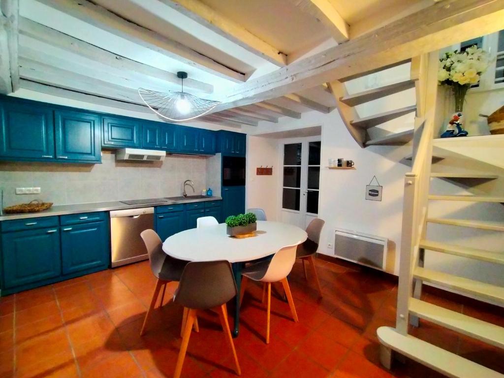 a kitchen with blue cabinets and a white table and chairs at Gîte Eloquent in Gratot