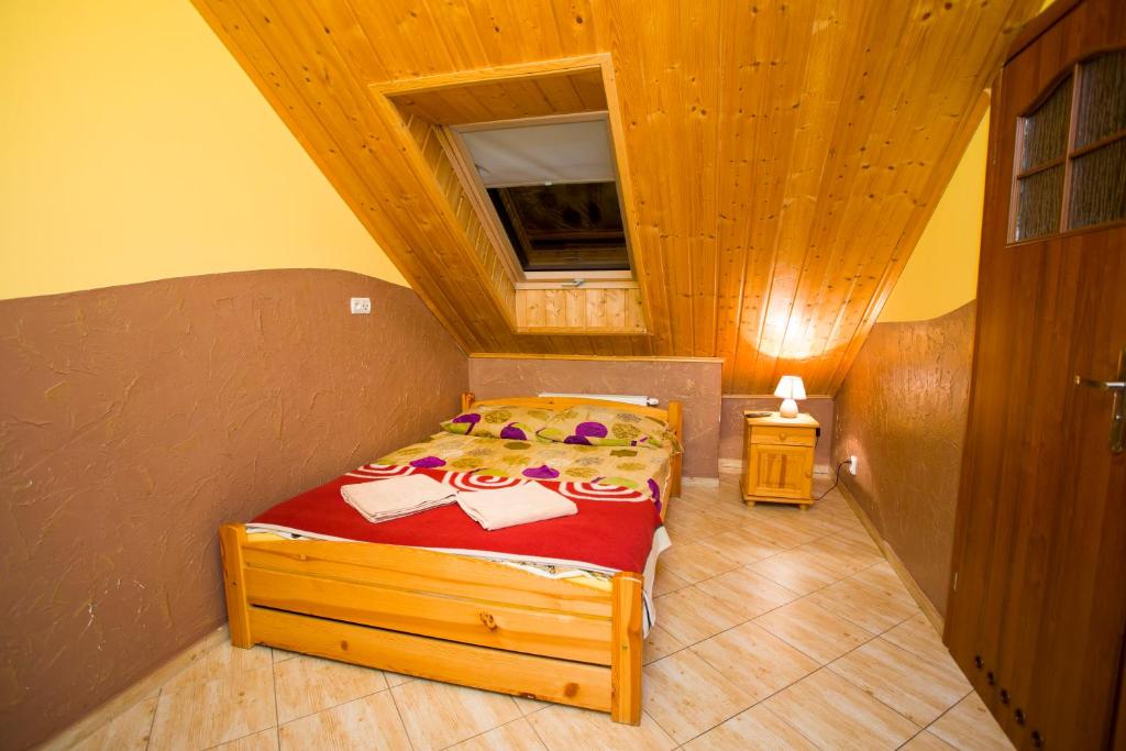 sypialnia z łóżkiem i drewnianym sufitem w obiekcie Karczma Chęciny w Chęcinach