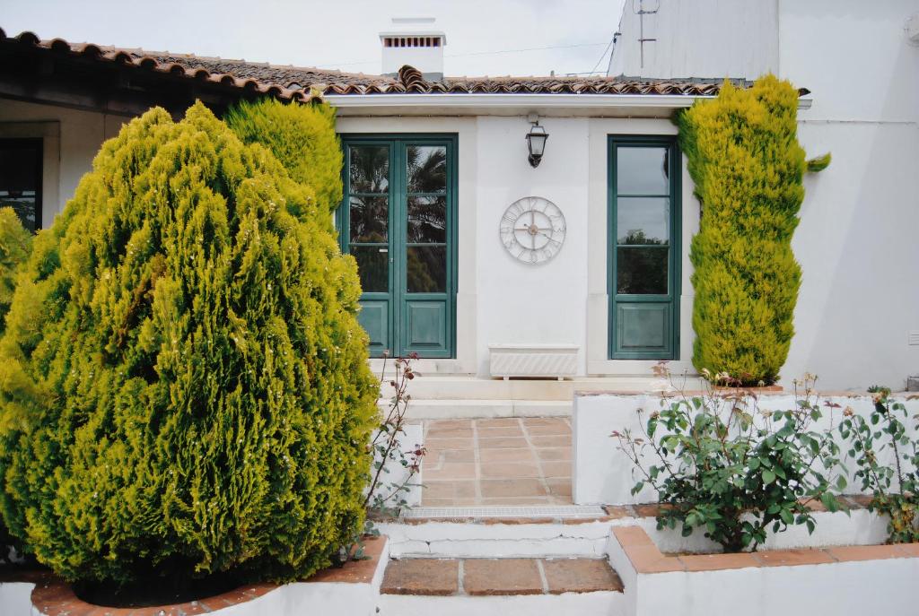 een wit huis met groene deuren en bomen bij Quinta de São Pedro de Tomar in Tomar