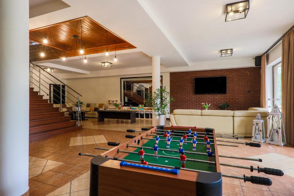 Spacious game room featuring foosball table foreground, staircase, seating area and wall-mounted TV.