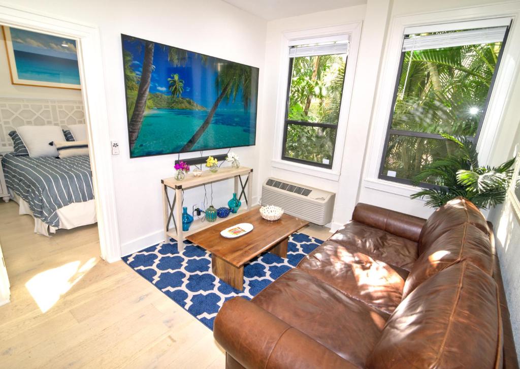 Tropical Beach Condo - Pool, Parking, 86" TV, WiFi في بالم بيتش: غرفة معيشة مع أريكة جلدية وطاولة