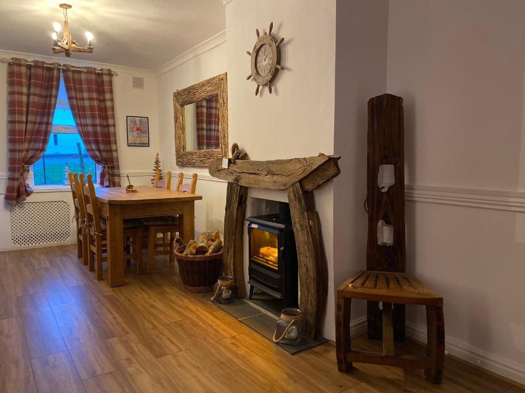 a living room with a fireplace and a dining room table at Sea View Cottage Lake District coast Haverigg in Millom