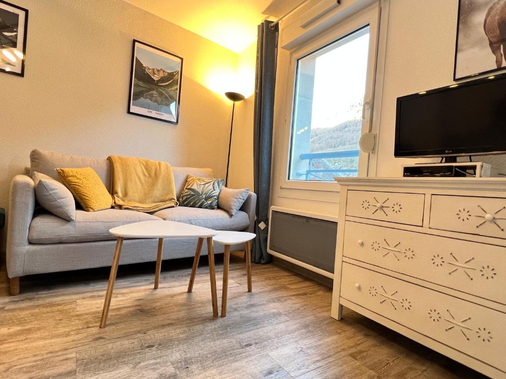 un salon avec un canapé et une télévision dans l'établissement Centre ville, T2 avec terrasse et parking couvert., à Cauterets