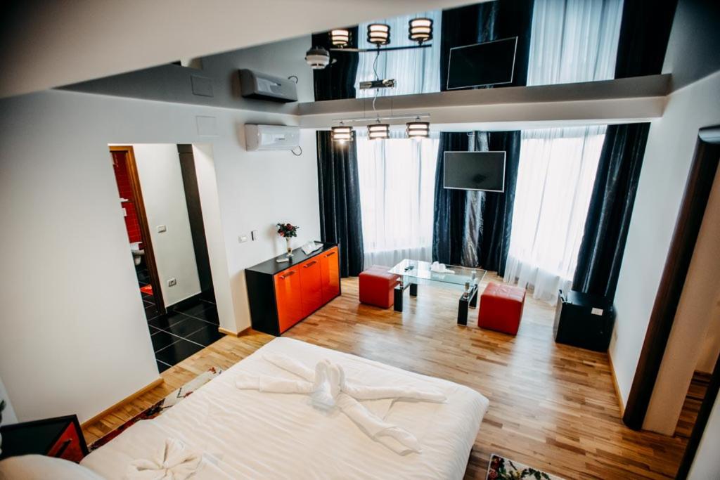 a bedroom with a large bed and a living room at Pensiunea Jacqueline in Târgu Jiu
