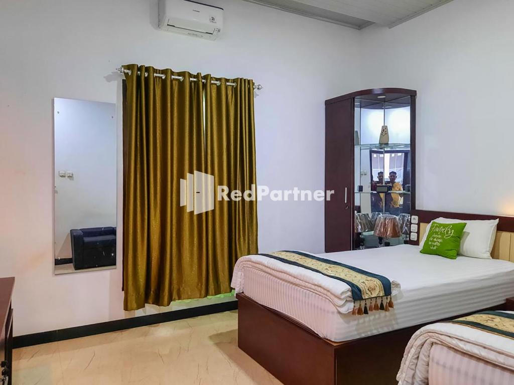 a bedroom with two beds and a yellow curtain at Wisma Auliyah Kolaka Utara Mitra RedDoorz in Susua