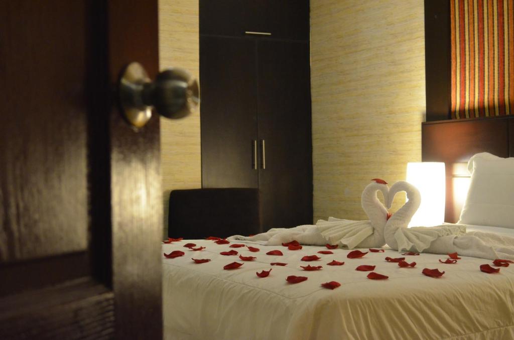 dos cisnes sentados sobre una cama con rosas en Monterrico Hotel Perú en Lima
