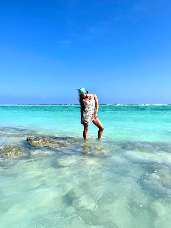 a woman standing in the water in the ocean at PRIV Fodhdhoo in Fodhdhoo
