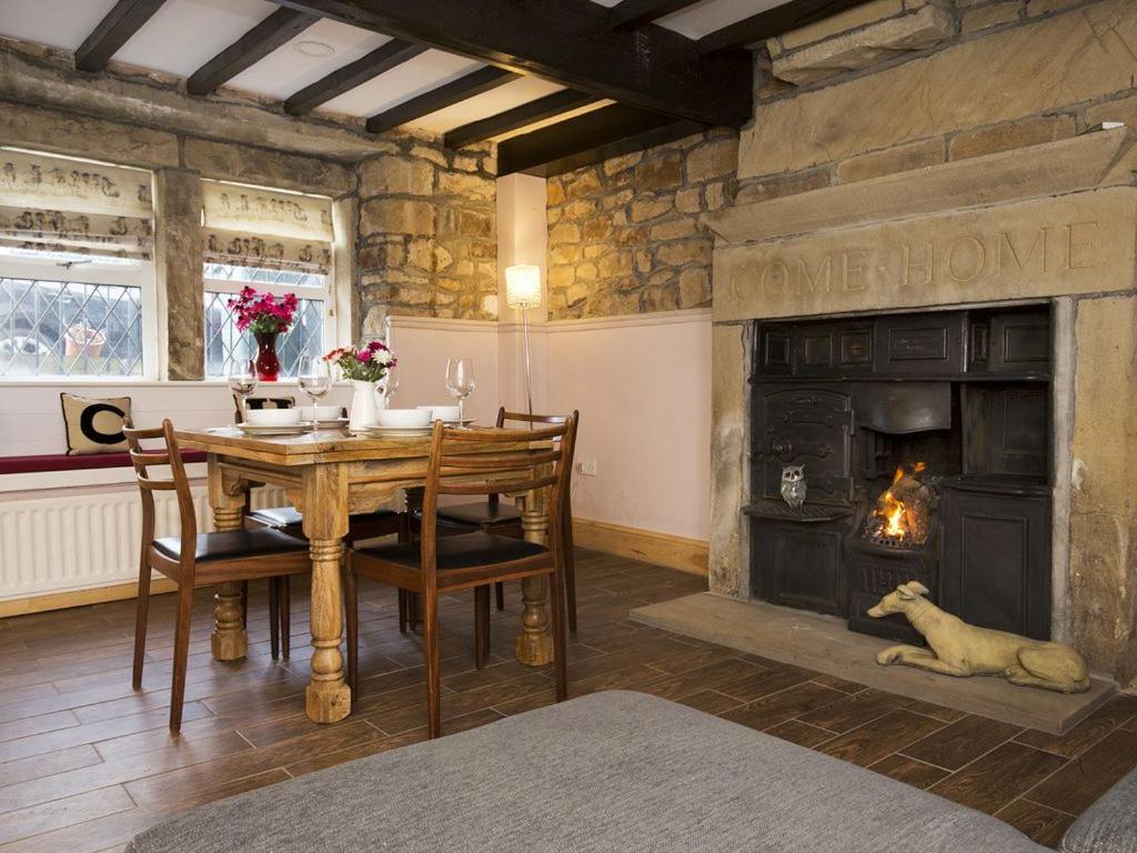 a dining room with a table and a fireplace at The Yorkshire Hosts - Come Home Cottage in Haworth
