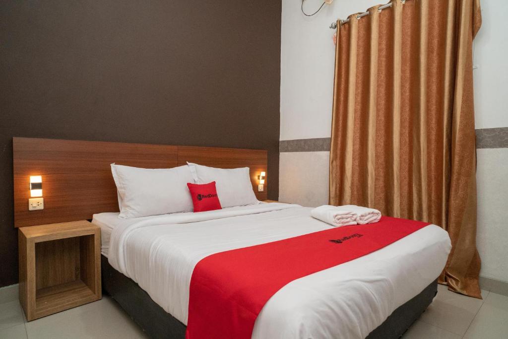 una camera da letto con un grande letto con una coperta rossa di RedDoorz Syariah near Kota Cinema Mall Jatiasih 