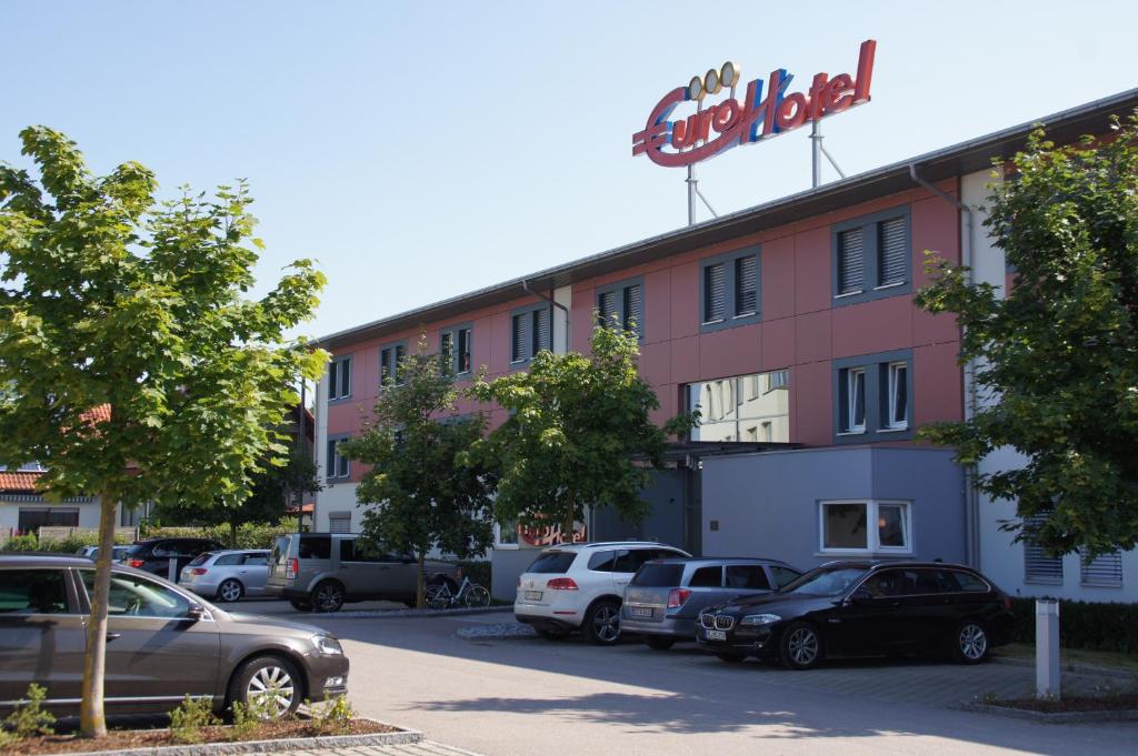 un edificio con coches estacionados en un estacionamiento en EuroHotel Günzburg, en Günzburg