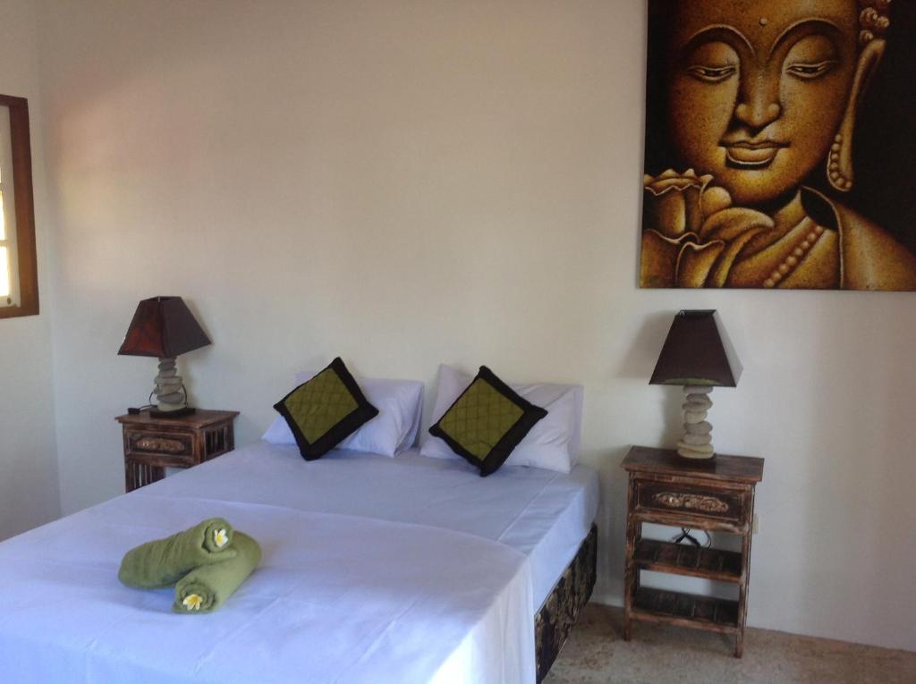a bedroom with two beds with a picture on the wall at Elephant House and Bungalows Gili Air in Gili Air