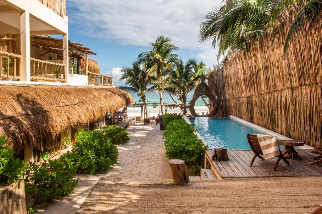 a resort with a swimming pool and palm trees at Dune Boutique Hotel located at the party zone in Tulum