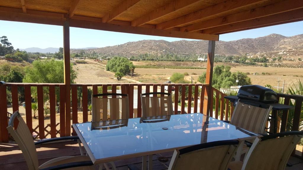 a table on a deck with a view of the mountains at Casabellavista Home, and Bungalows in Valle de Guadalupe