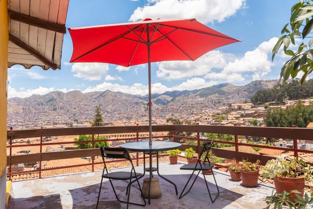 een tafel en stoelen met een rode parasol op een balkon bij Samay Wasi Hostel I in Cuzco