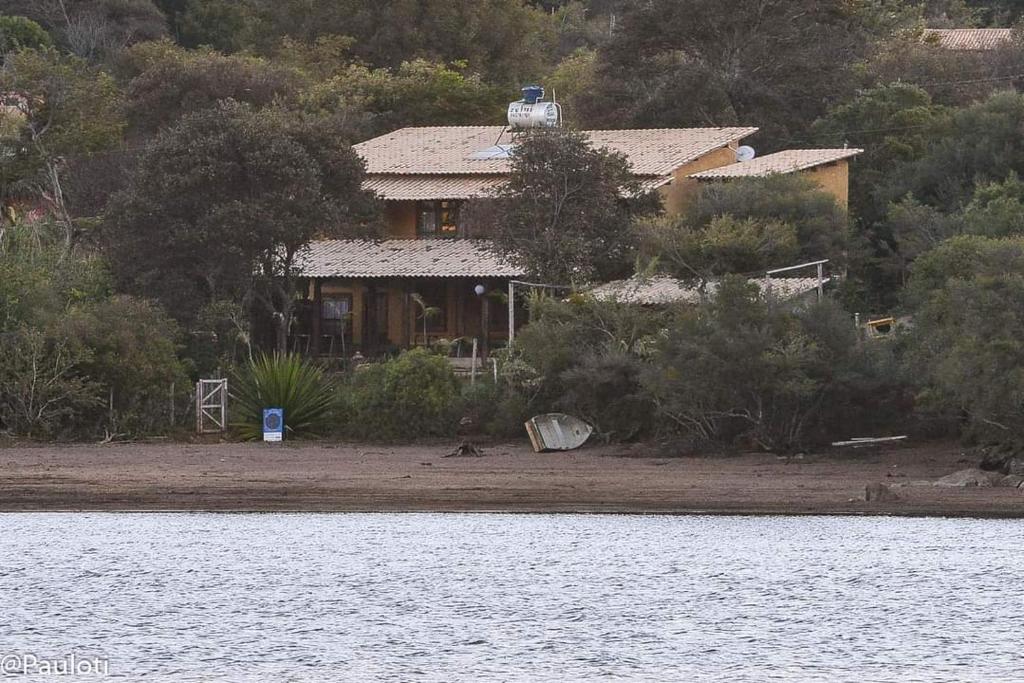 a house on the shore of a body of water at Casas e apartamentos da Praia, Lapinha na beira do lago in Santana do Riacho