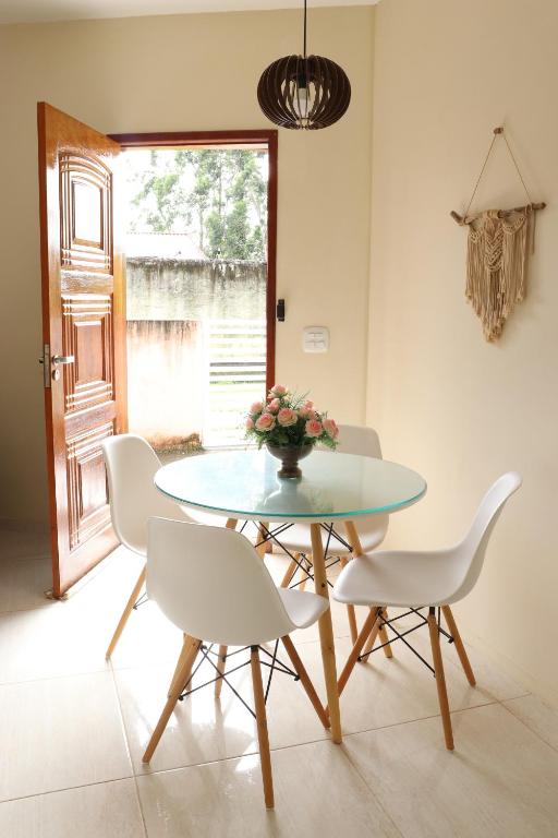 a dining room with a glass table and white chairs at CASA DOS BONS VENTOS - À 6 minutos da praia de carro in Itaipuaçu