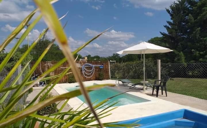 een zwembad met een parasol en een tafel en stoelen bij Cabanas Valle Azul in Villa Rumipal