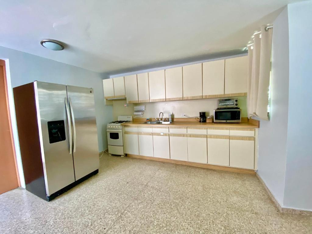 uma cozinha com armários brancos e um frigorífico de aço inoxidável em Bee Inn Puerto Rico Charming Urban Apartment in San Juan em San Juan