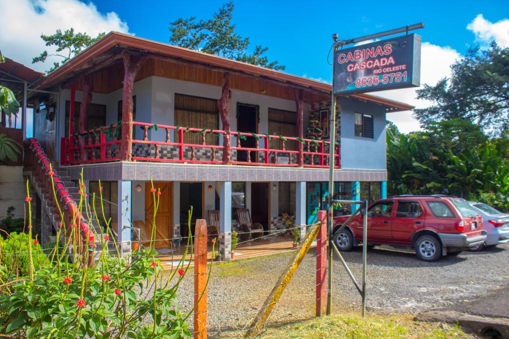 un edificio con un coche rojo estacionado frente a él en Cabinas Cascada Rio Celeste, en Bijagua