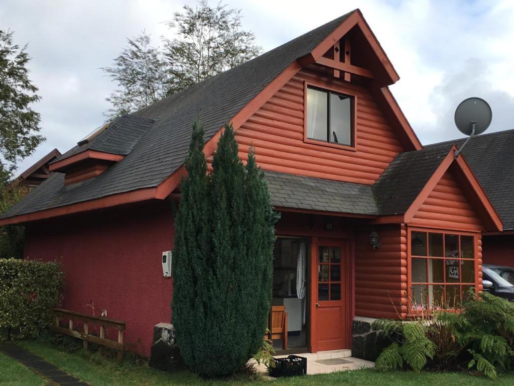 a red house with a black roof at Hermosa casa en Condominio in Pucón