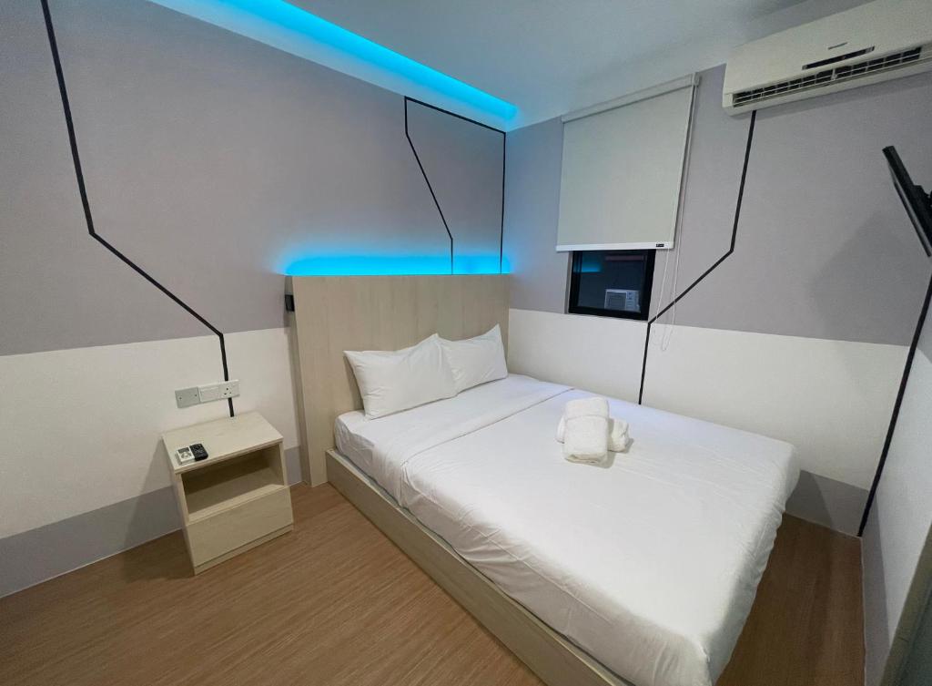 a small bedroom with a white bed with a blue light at GG Hotel Bandar Sunway in Petaling Jaya
