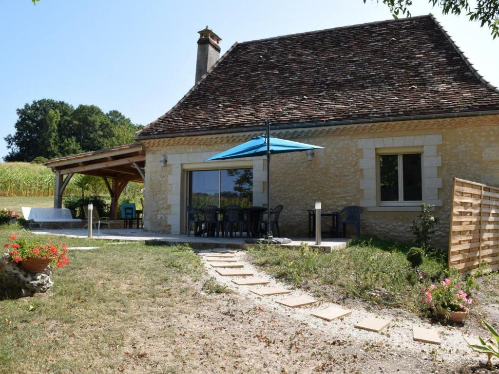 ein Haus mit einem Tisch und einem blauen Regenschirm in der Unterkunft Gîte Saint-Pierre-de-Chignac, 3 pièces, 6 personnes - FR-1-616-18 in Saint-Pierre-de-Chignac