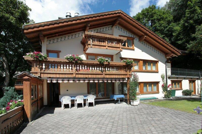 a house with a balcony and a table and chairs at Ariola in Klosters