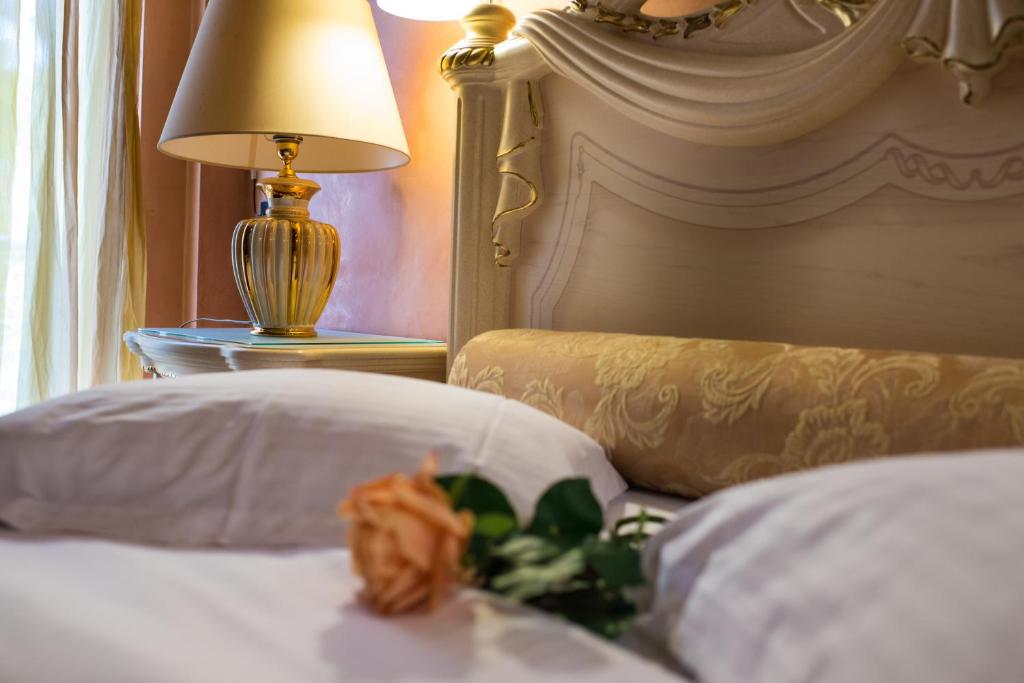 Anastazia Luxury Suites & Spa في أثينا: سرير عليه مصباح وزهرة