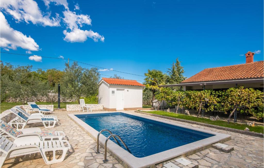 a swimming pool with chairs and a house at Awesome Home In Malinska With Outdoor Swimming Pool in Gostinjac