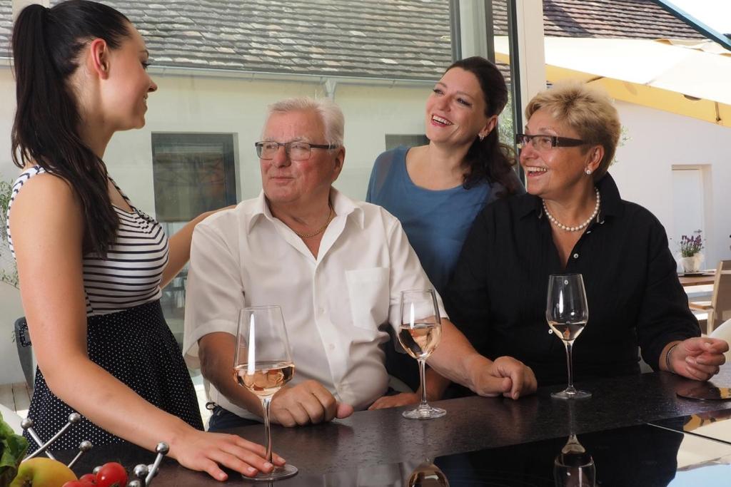 un gruppo di persone che si trovano intorno a un tavolo con bicchieri da vino di Hotel Krug a Gumpoldskirchen