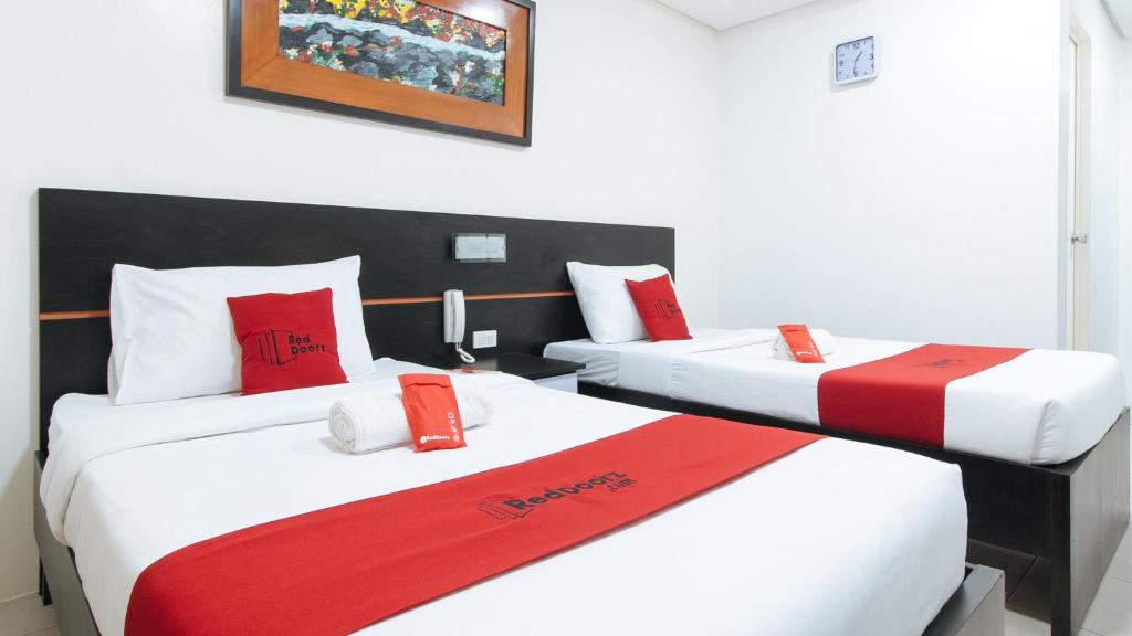 two beds in a hotel room with red and white pillows at RedDoorz @ Greenview Hotel and Restobar Masbate in Masbate