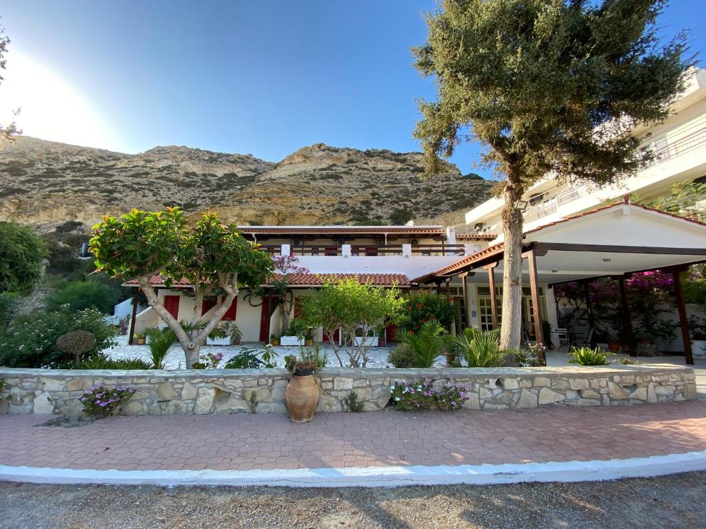 a building with a tree and a stone wall at Pension Romantika in Matala