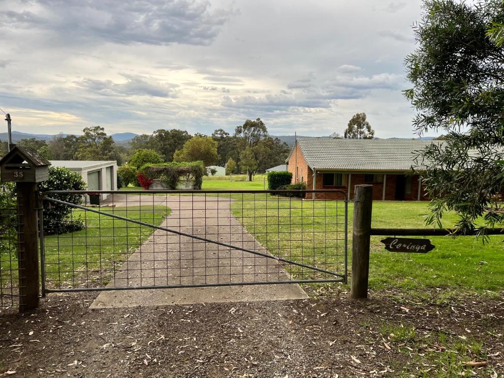 a fence in front of a house with a driveway at Carinya Cottage Hunter Valley - Nature retreat in Aberdare