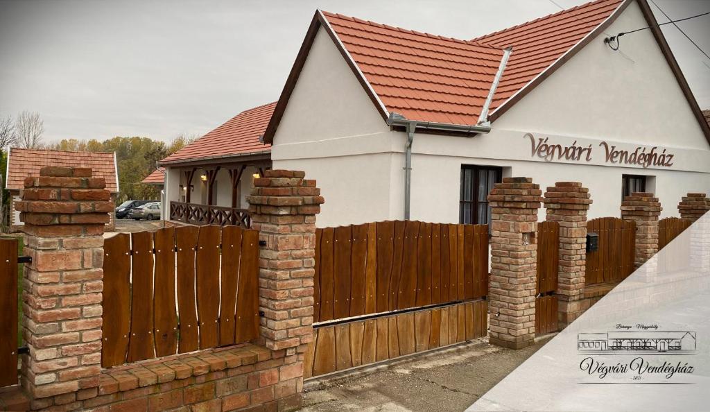 una casa con una puerta de madera y una valla en Végvári Vendégház, en Magyarbóly