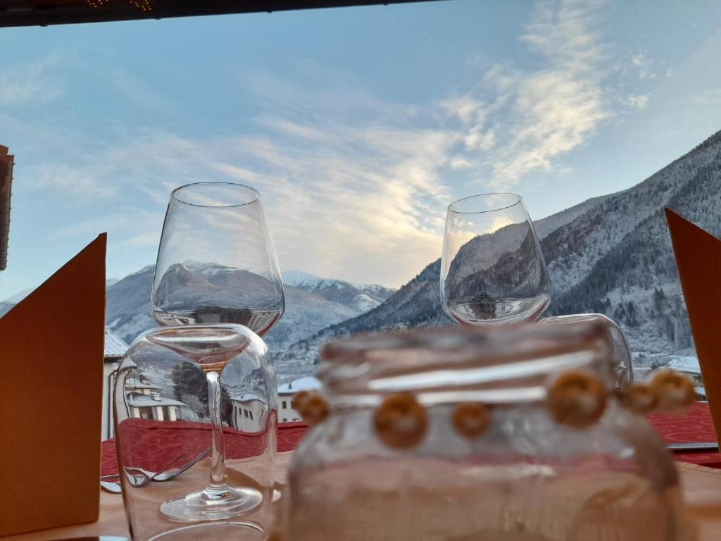 two wine glasses on a table with a view of mountains at Hotel Del Negro in Sùtrio