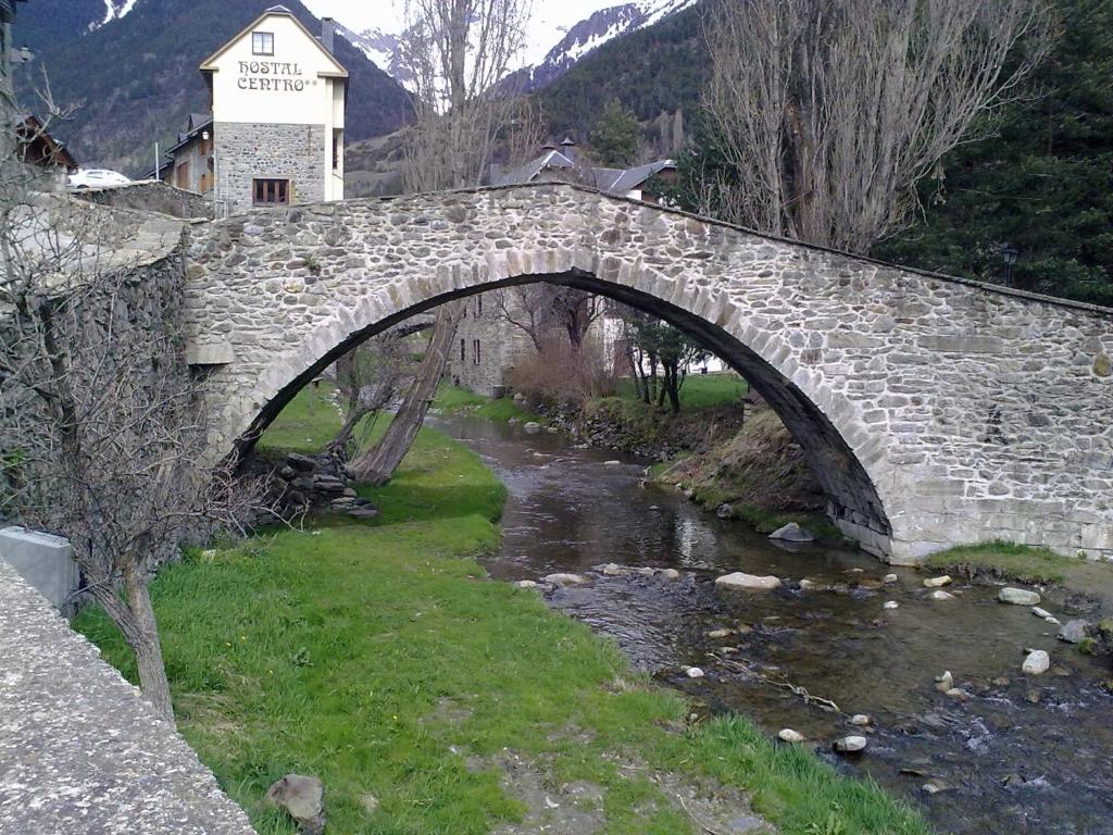 un pont en pierre sur un ruisseau avec une rivière dans l'établissement Hostal Centro, à Sallent de Gállego