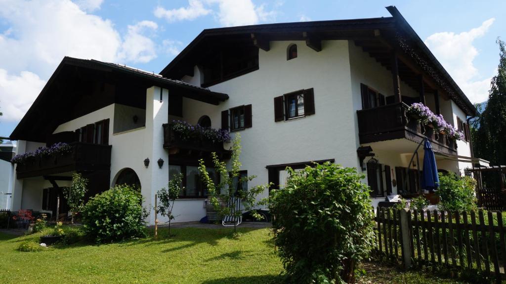 ein weißes Haus mit schwarzen Fenstern und einem Zaun in der Unterkunft Gästehaus Brigitte in Garmisch-Partenkirchen