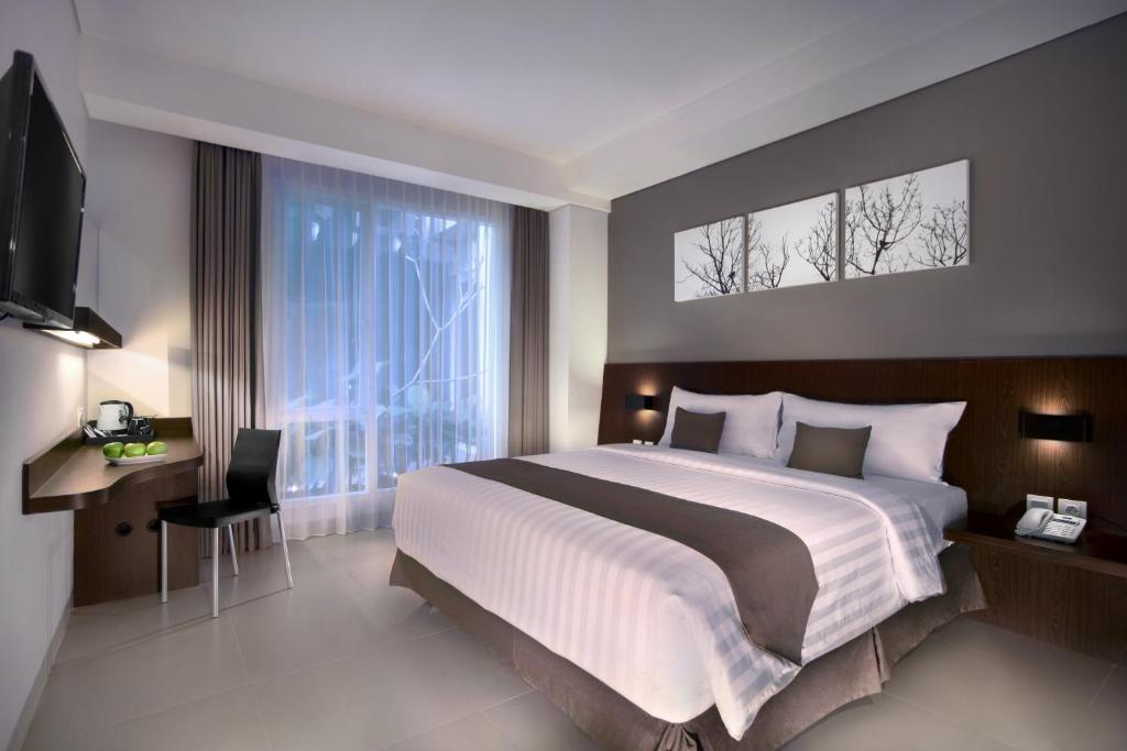 een slaapkamer met een groot bed en een groot raam bij Neo Denpasar by ASTON in Denpasar