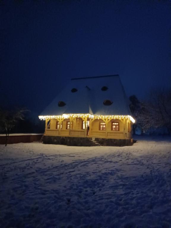 a house covered in lights in the snow at night at Pensiunea Agroturistica Casa Pribegilor in Breb