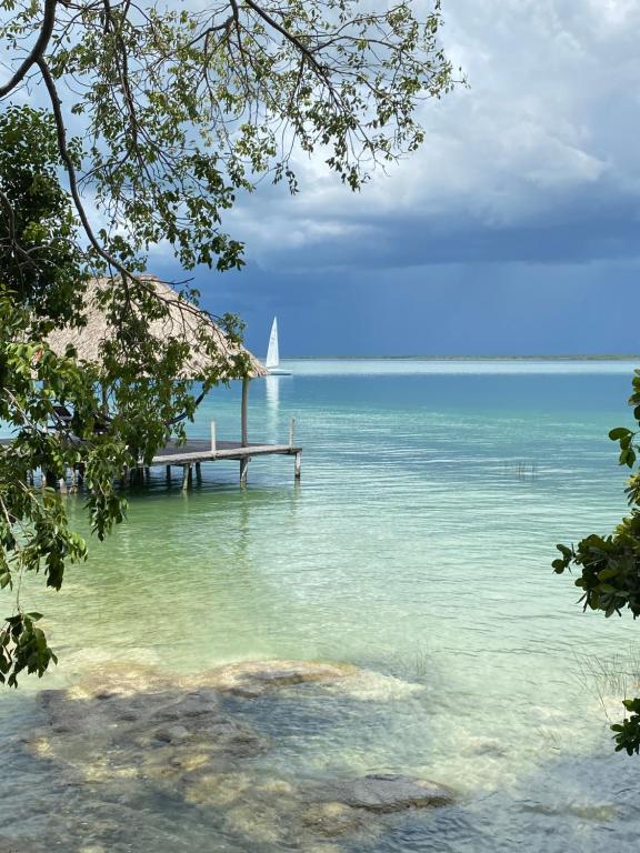 a sail boat on the water with a dock at Pucté Bacalar in Bacalar