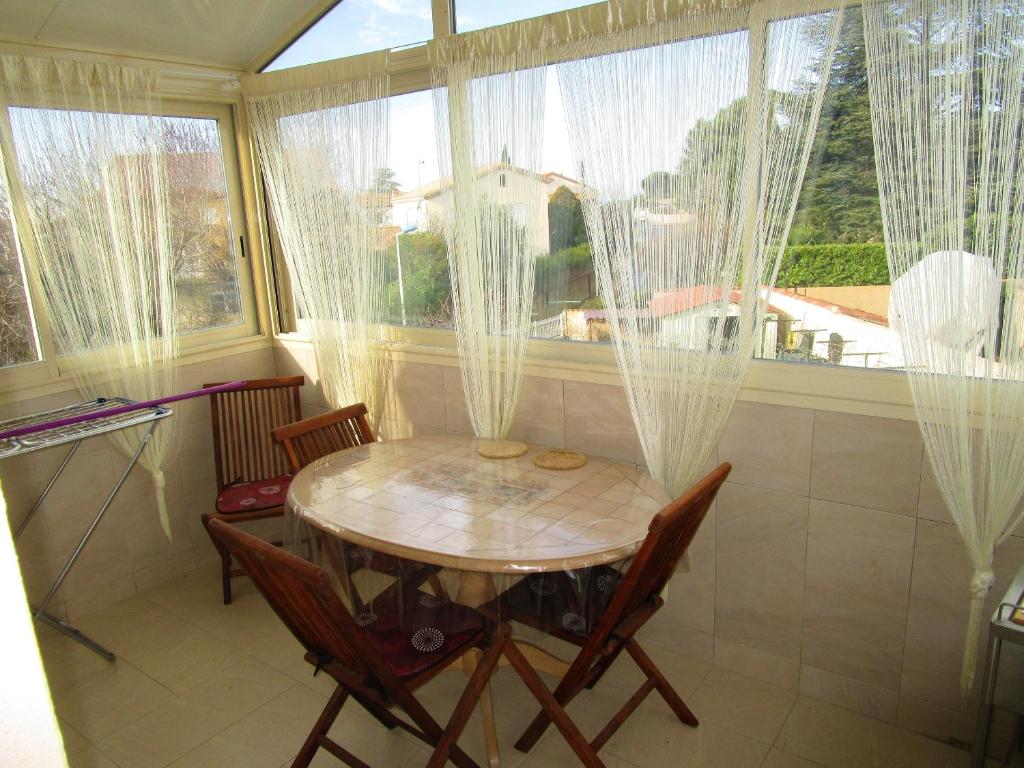 une table et des chaises dans une pièce avec des fenêtres dans l'établissement Appartement élégant à Vias avec balcon et jardin, à Vias
