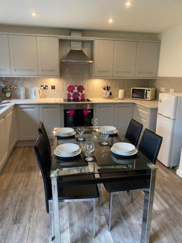 a kitchen with a table and chairs and a kitchen with white cabinets at Doc Y Gogledd in Llanelli