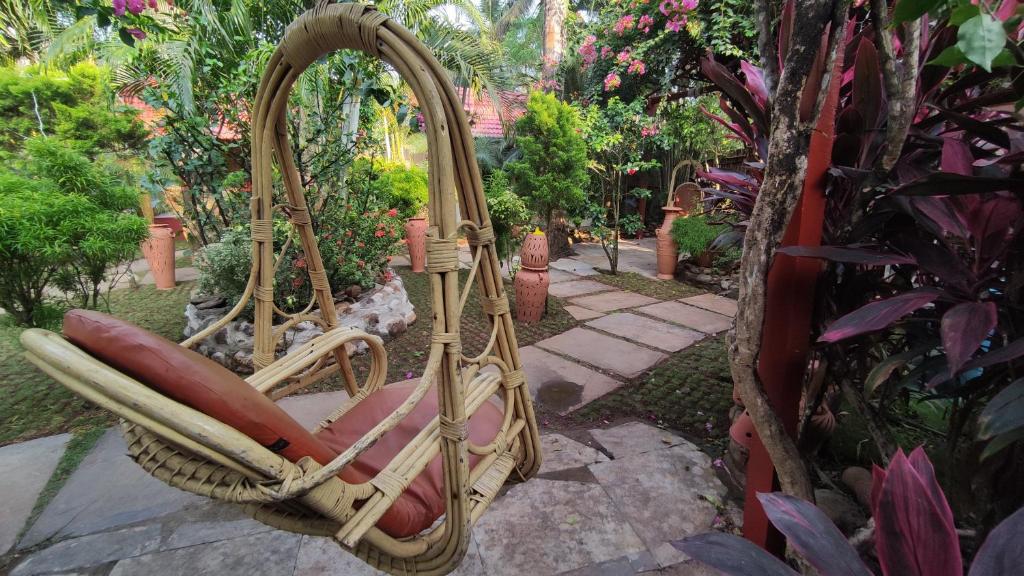 a wicker chair sitting in the middle of a garden at Shawnels Beach Resort in Palolem