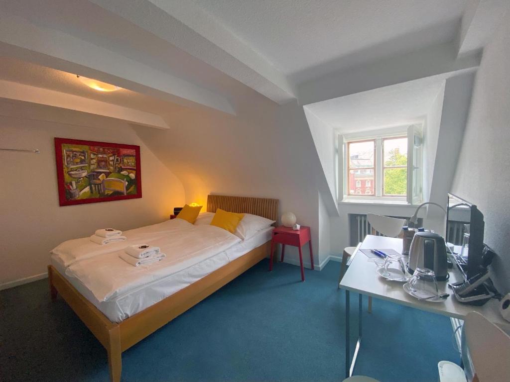 a bedroom with a bed and a desk and a television at Frauenhotel Hanseatin - Women Only in Hamburg