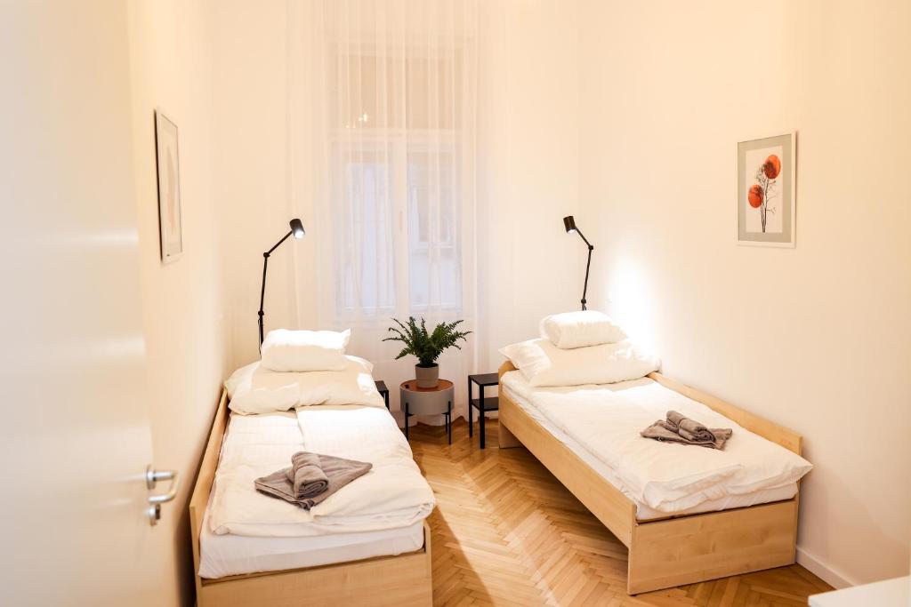 ブダペストにあるCentral 3 bedroom apartment for 6 guests - AC, Wi-Fi, Self check in-out, Professional hostsの白い壁とウッドフロアの客室で、ベッド2台が備わります。