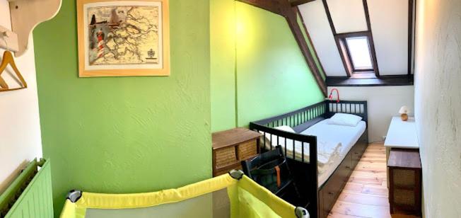 a room with a green wall with a crib and a bedroom at Ysermonde Fisherman's Cottage in Nieuwpoort