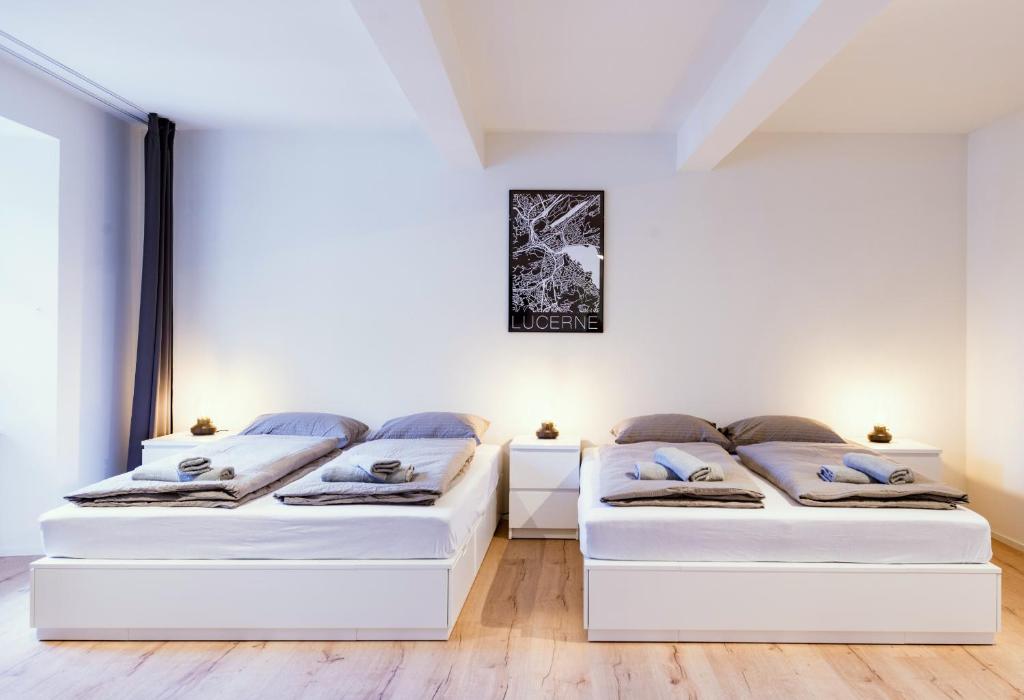 two beds in a white room with wooden floors at HITrental Zur Metzgern Apartments in Lucerne